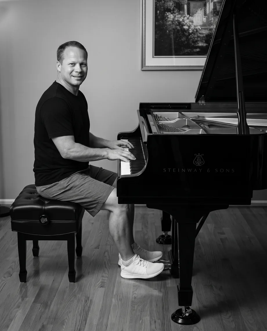The owner of JLP Civil seated at a Steinway grand piano